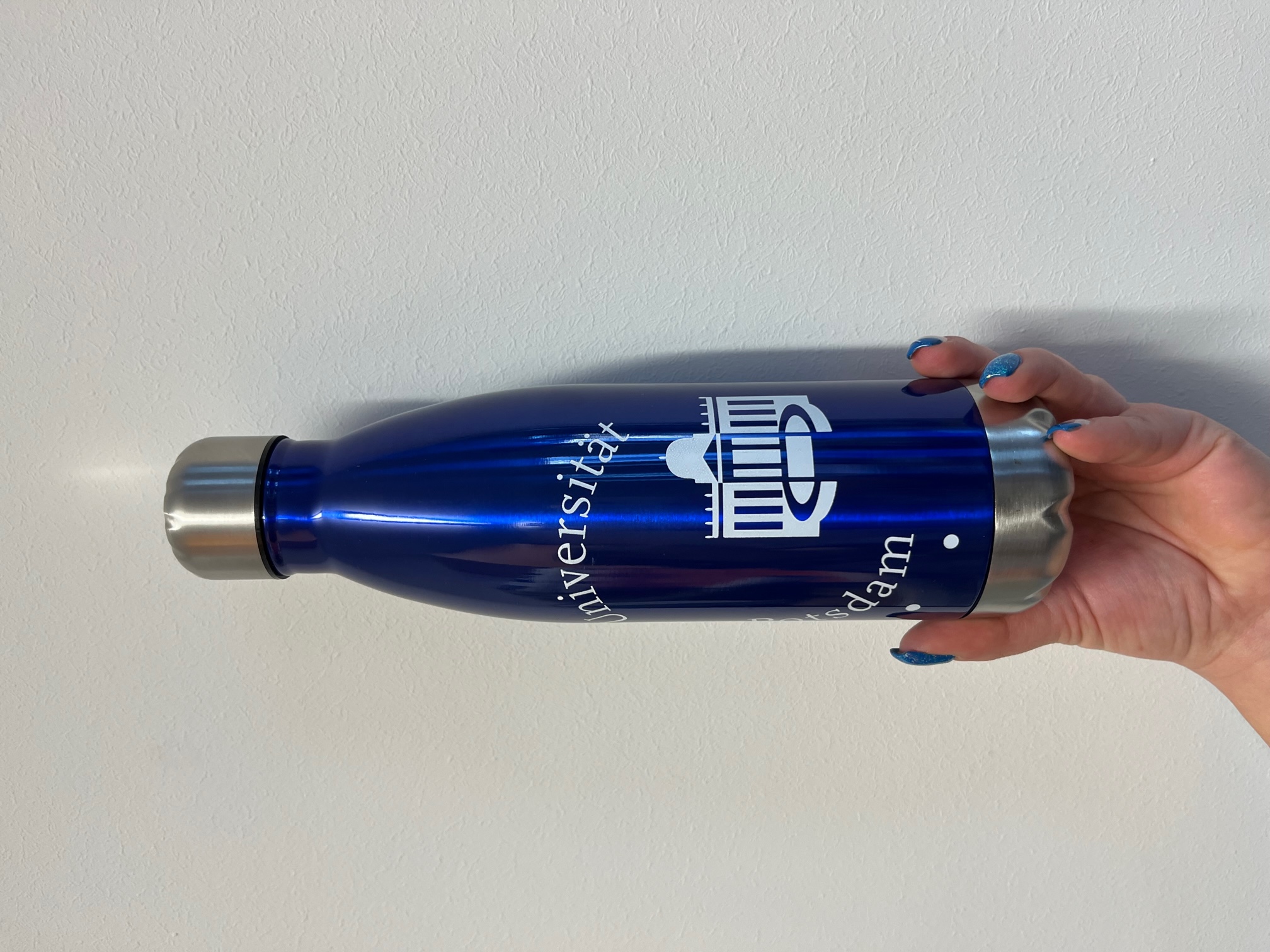 Edelstahlflasche-logo-blau. Abgebildet ist eine blaue Edelstahlflasche mit  groß aufgedrucktem Universitätslogo in der Mitte.